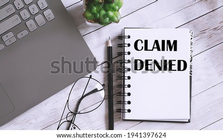 Register CLAIM DENIED text on the notebook with office background