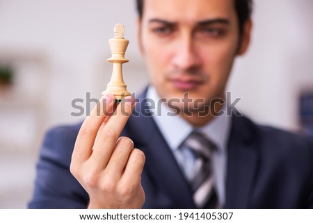 Young male employee playing chess at workplace