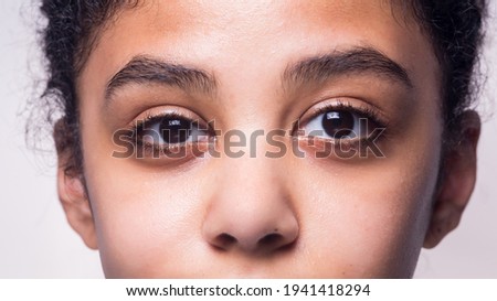 A close up of the eyes of an Afro American teenage girl isolated on a  grey background Royalty-Free Stock Photo #1941418294