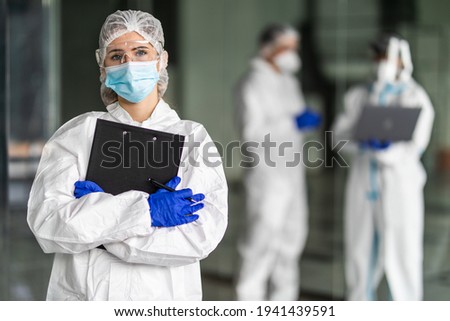 Disease control employees in protective clothing during coronavirus Coivd-19 epidemic in a clinic Royalty-Free Stock Photo #1941439591