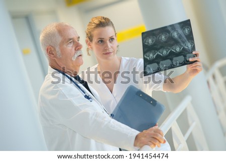 medic and assistant looking at x-ray Royalty-Free Stock Photo #1941454474