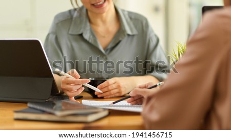 Cropped shot of two female office worker consulting other work while sitting opposite each other in office room