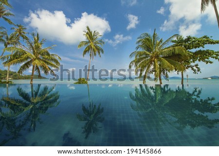 Beautiful reflection of coconut trees and blue sky on the swimming pool at the beach, Mak Island, Thailand 