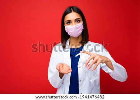 Doctors advice and health protection during coronavirus epidemic. Young woman doctor in protective mask, white coat shows antiseptic in her hands, isolated on background