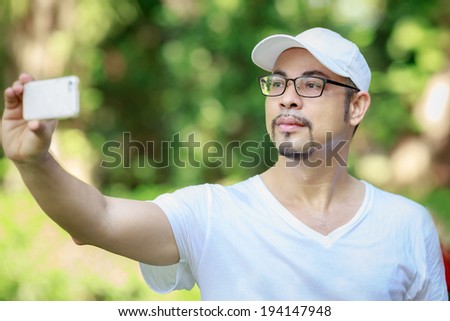 man photographer by smartphone wear white t-shirt and hat,The man eyeglasses , photograph natural and yourself after runing on the park in the morning