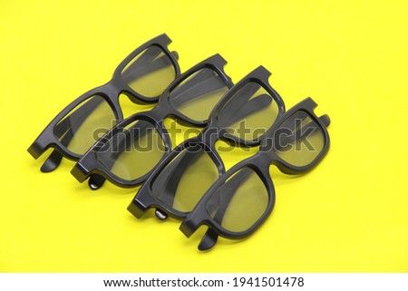 Modern sunglasses in black frames with a large plan. glasses for 3D movies. Stylish glasses on a yellow background. Optics. Flat styling style. Copyspace.