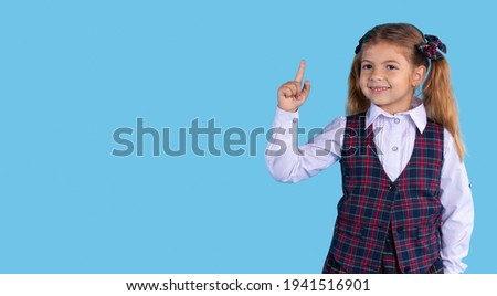 Banner,long format. Caucasian girl of elementary grades in a school phonerm points up with her index finger. Blue background and space for your ad or text.