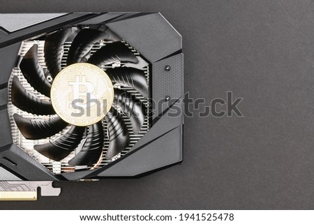 Silver Bitcoin coin on a Black video Card on a gray background. Crypto currency, close up. Bitcoin mining concept