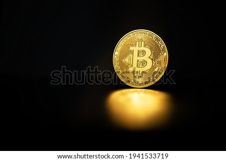 Physical shiny bitcoin agains dark background closeup