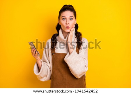 Photo of nice brunette impressed curly hairdo lady hold telephone hand face wear sweater isolated on yellow color background