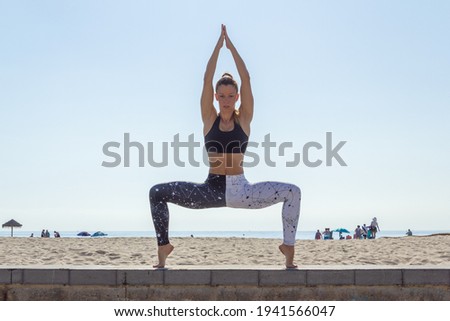 A former dancer woman does yoga on the beach, does poses, splits, L-sits, squats, lunges and some jumps.