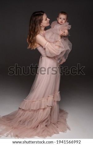 Portrait of happy mother with her baby isolated on grey.family, child and parenthood concept - happy smiling young mother with little baby at studio.Portrait of young mother and her baby.