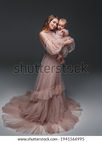 Portrait of happy mother with her baby isolated on grey.family, child and parenthood concept - happy smiling young mother with little baby at studio.Portrait of young mother and her baby.