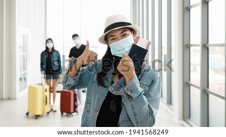 Asian tourist woman wearing protective mask at airport during virus pandemic. Required face mask at departure hall of airport during virus COVID-19 pandemic. Royalty-Free Stock Photo #1941568249
