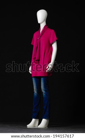 full-length female mannequin dressed in red dress and jeans on black background 