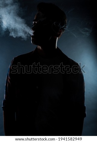 Handsome stylish man wearing checkered shirt and smoking a cigarette