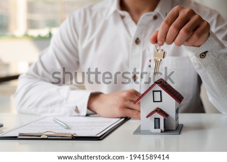 Real Estate Broker Home insurance or a home salesman holding a house key, Mortgage loan approval home loan and insurance concept.