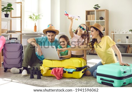 Happy excited family and daughter children buying payment for flight ticket booking hotel online using laptop with travel suitcase around at home living room. Holiday vacation traveling abroad concept Royalty-Free Stock Photo #1941596062