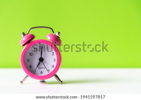 Alarm pink vintage alarm clock falling on the floor with green color background, copy space for tex.  Morning and Start up Concept