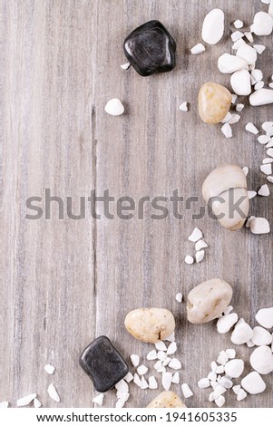 White, black decorative rocks and pebbles over grey wooden background. Top view, flat lay. Copy space