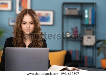 Happy young woman sit at desk look at laptop screen browsing surfing wireless Internet at home, smiling millennial female employee work on modern computer in living room, technology concept