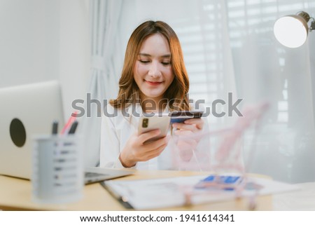 Young woman holding credit card and using laptop computer. Businesswoman or entrepreneur working at home.