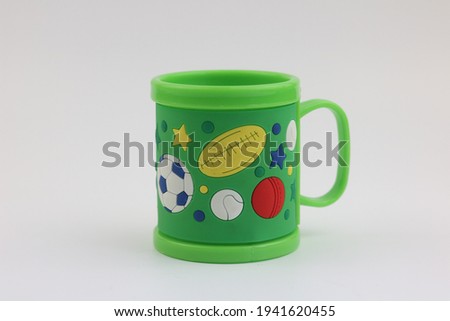 Green mugs and pictures of some kind of ball on white background. Selective focus.