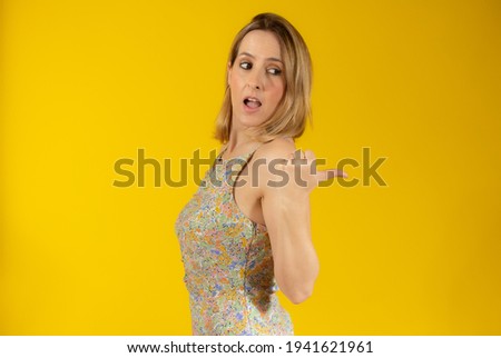 Smiling pretty young woman showing thumb up isolated over yellow background