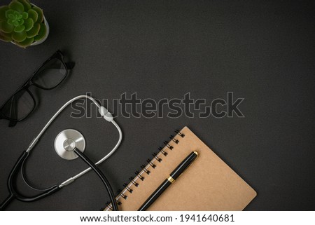 A stethoscope and notebook on black background with a copy space. Flat lay.