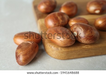 Raw jackfruit seeds and wooden board on light table, closeup