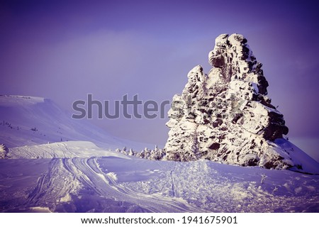 stone rock in winter frost covered with snow on blue sky background