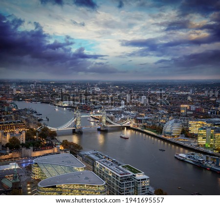 Elevated night view to the lit Tower Bridge of London, United Kingdom, with a cloudy sky