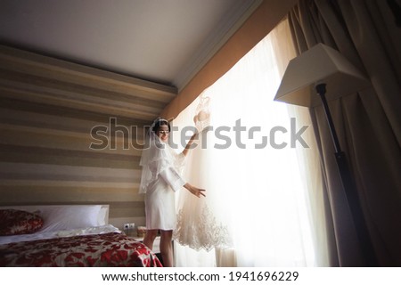 Morning of the bride. Bride's fees. The bride admires and touches her dress.