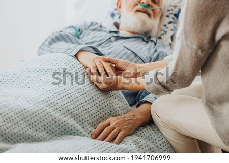 Close-up of older dying man holding his wife's hands Royalty-Free Stock Photo #1941706999