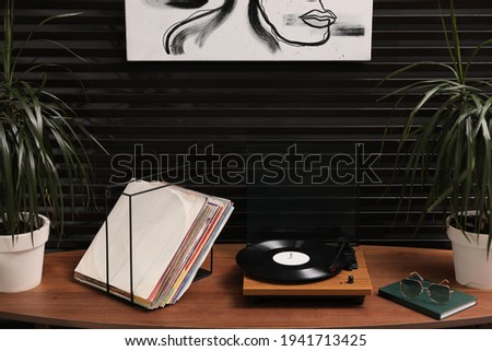 Stylish turntable with vinyl discs on table in room Royalty-Free Stock Photo #1941713425