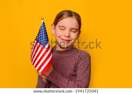 Happy kid girl 6 y.o. holds American Flag Background. Expression of Patriotism and Love for their Country, the United States. June 14