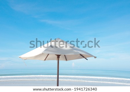 Umbrella at the beach, summer season background concept, big white umbrella against beautiful blue clear sky with space, layer color of sea, waves, sand, clean picture nice colour, beautiful scenery 