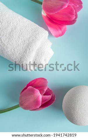 Skin care products on a blue background. Natural cosmetics and pink tulips. Place for text.