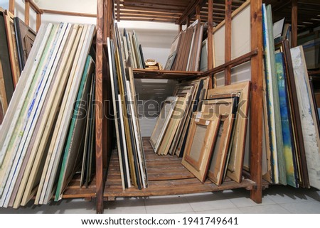 Wooden shelves at art gallery storage full of pictures and art equipment