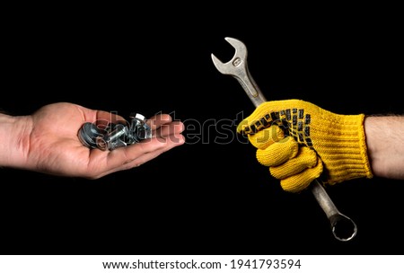 Close-up of people is hands, one holding a wrench and the other holding bolts and nuts. The concept of starting renovation or construction