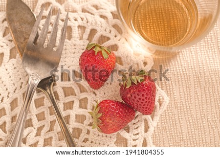 A concept photo of three strawberries and old tarnished silverware.