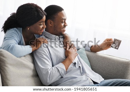 Side view of black man and woman looking at sonogram