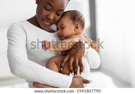 Portrait of black mother holding crying baby on hands Royalty-Free Stock Photo #1941807790
