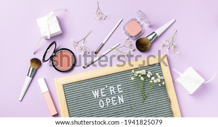 Text We are open on the letterboard with decorative cosmetic and make up tools. Beauty salon reopening concept. Cosmetic store opening banner.