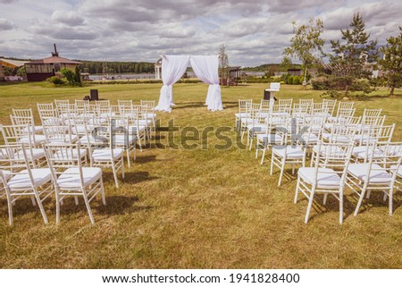 a beautifully decorated wedding ceremony, a floral wedding arch and chairs