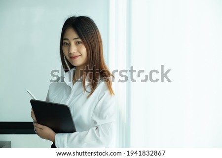 Young businesswoman sitting on modern workplace and looking at camera.