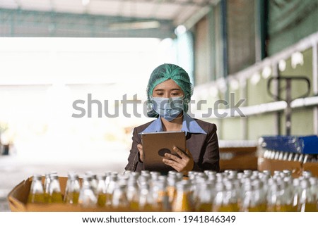 Asian female employee worker wearing mask and hairnet using digital table checking product of Basil seed with fruit in beverage factory industry. Inspection quality control