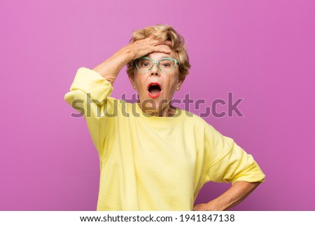 old pretty woman panicking over a forgotten deadline, feeling stressed, having to cover up a mess or mistake Royalty-Free Stock Photo #1941847138