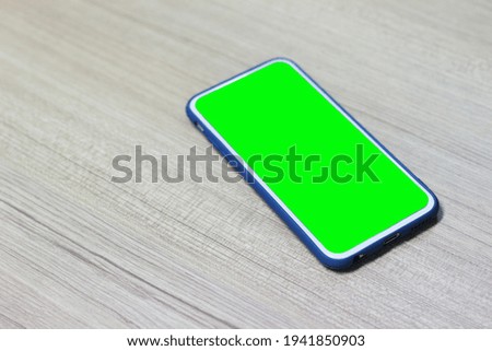blank green screen mobile phone on wood background