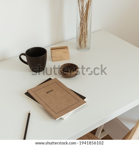 Women's home office workspace. Freelance work, business workplace. Light aesthetic hygge space with wooden chair, table, reed pampas grass bouquet, mug, notebook. Modern interior design.